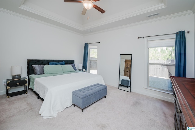 carpeted bedroom with a tray ceiling, ceiling fan, and ornamental molding