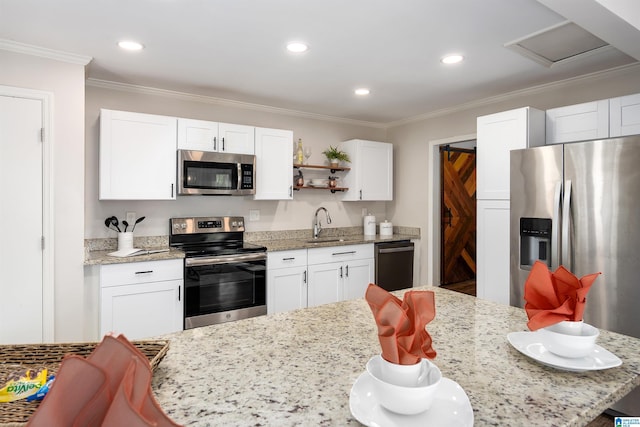 kitchen with white cabinets, sink, ornamental molding, light stone counters, and stainless steel appliances