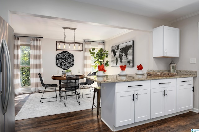 kitchen with white cabinets, light stone counters, decorative light fixtures, dark hardwood / wood-style flooring, and stainless steel refrigerator