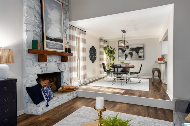 living room featuring ornamental molding, a fireplace, and dark wood-type flooring