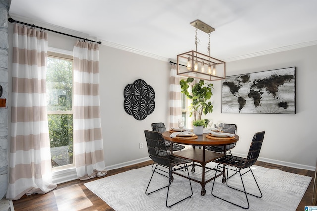 dining area with dark wood-type flooring, crown molding, and a notable chandelier