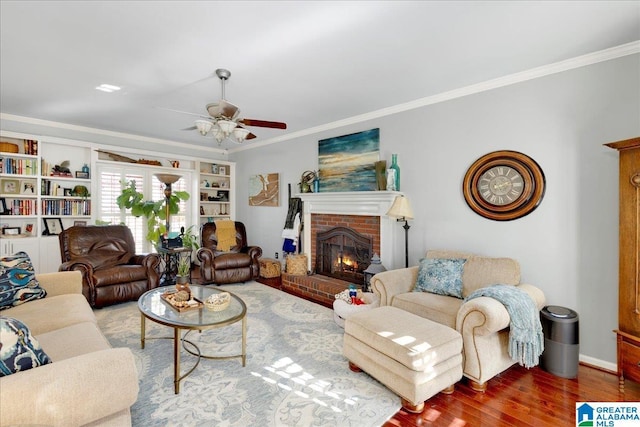 living room with ceiling fan, wood-type flooring, crown molding, and a fireplace