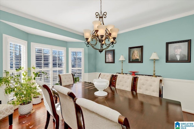 dining area with hardwood / wood-style flooring, ornamental molding, and an inviting chandelier