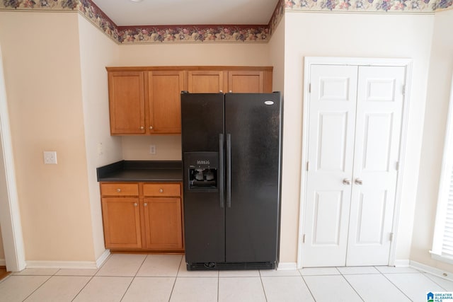 kitchen with light tile patterned floors and black refrigerator with ice dispenser