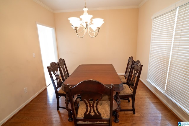 dining space featuring a chandelier, ornamental molding, and dark wood-type flooring