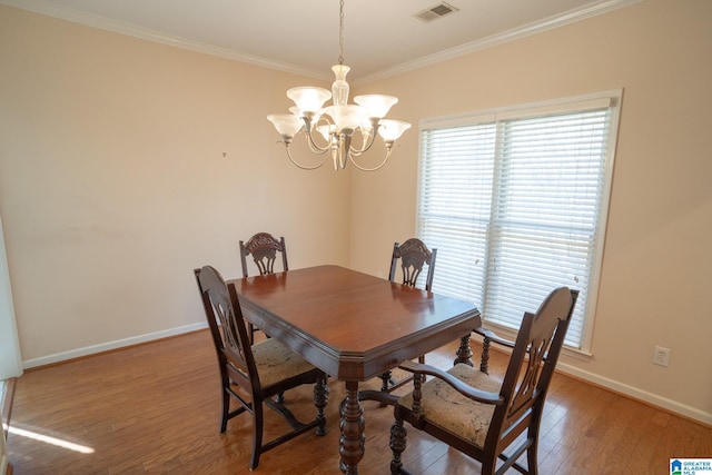 dining space featuring hardwood / wood-style flooring, crown molding, and a notable chandelier