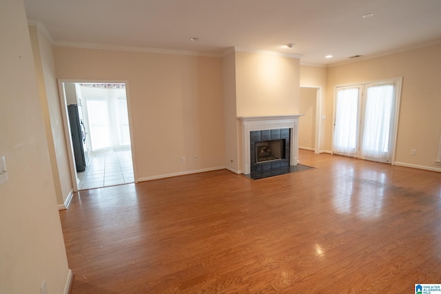 unfurnished living room featuring a tile fireplace, hardwood / wood-style flooring, and crown molding