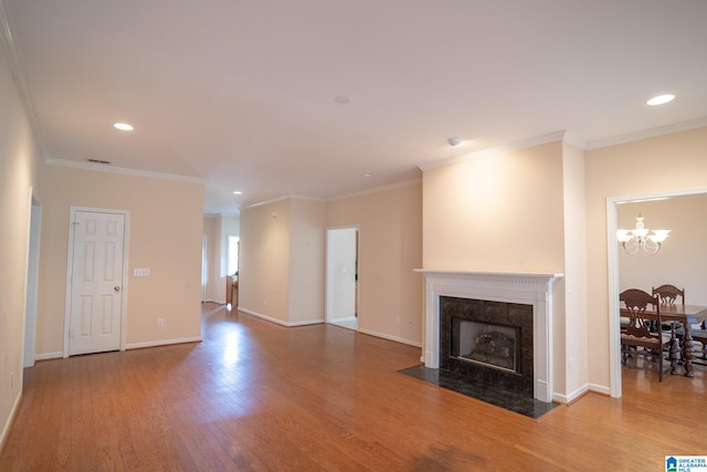 unfurnished living room featuring a fireplace, hardwood / wood-style floors, crown molding, and a notable chandelier