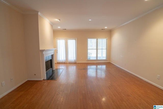 unfurnished living room with hardwood / wood-style floors, crown molding, and a fireplace