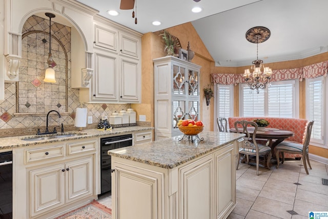 kitchen with pendant lighting, a center island, backsplash, cream cabinets, and sink