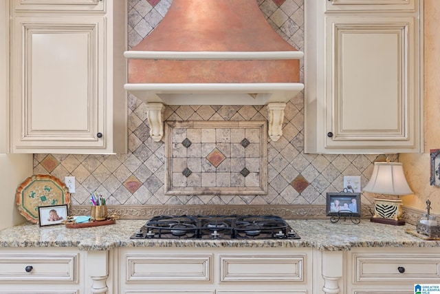 kitchen with black gas stovetop, cream cabinets, and light stone counters