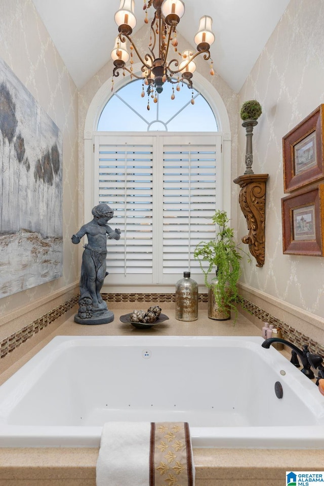 bathroom featuring a notable chandelier, a healthy amount of sunlight, and vaulted ceiling