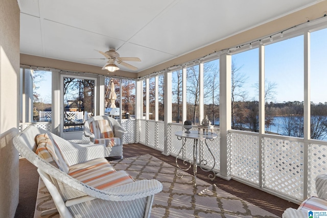 sunroom / solarium with ceiling fan and a water view