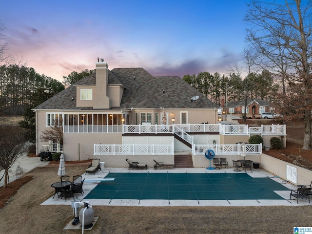 back house at dusk featuring a patio area and a covered pool