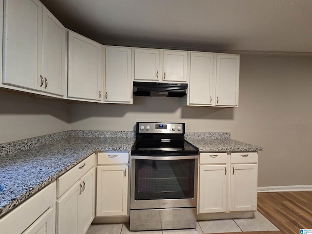 kitchen featuring white cabinets, light stone counters, electric stove, and light wood-type flooring