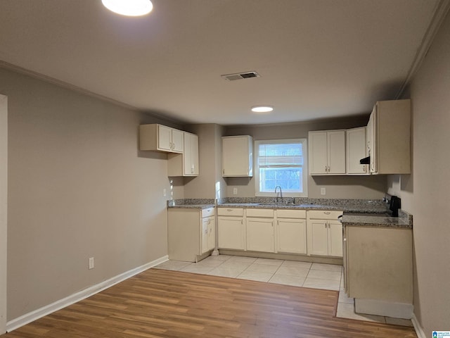 kitchen with white cabinetry, sink, and light hardwood / wood-style flooring