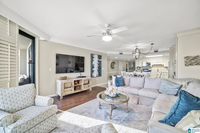 living room with ceiling fan with notable chandelier, dark hardwood / wood-style flooring, and ornamental molding