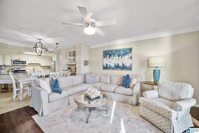 living room featuring crown molding and ceiling fan with notable chandelier