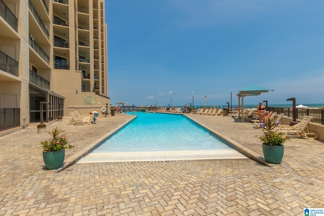 view of swimming pool with a patio and a water view