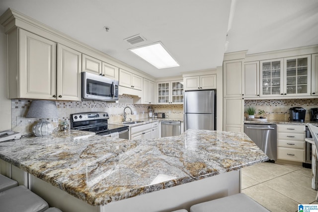 kitchen featuring light stone counters, sink, a breakfast bar area, and appliances with stainless steel finishes