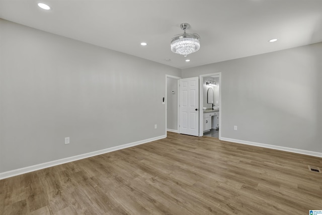 spare room with light hardwood / wood-style floors and an inviting chandelier