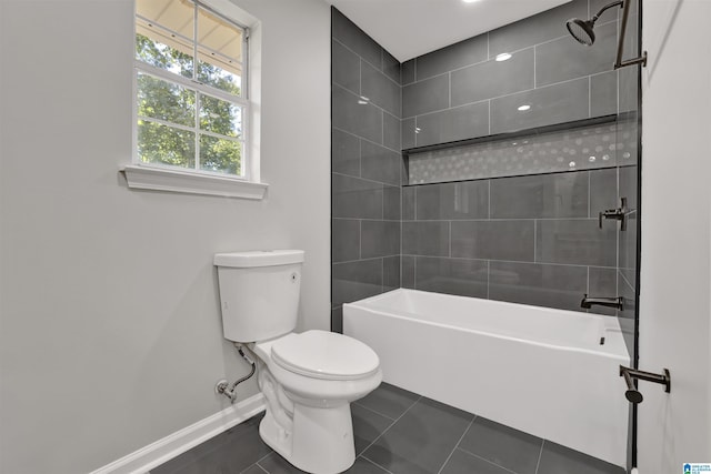 bathroom featuring tile patterned flooring, tiled shower / bath combo, and toilet