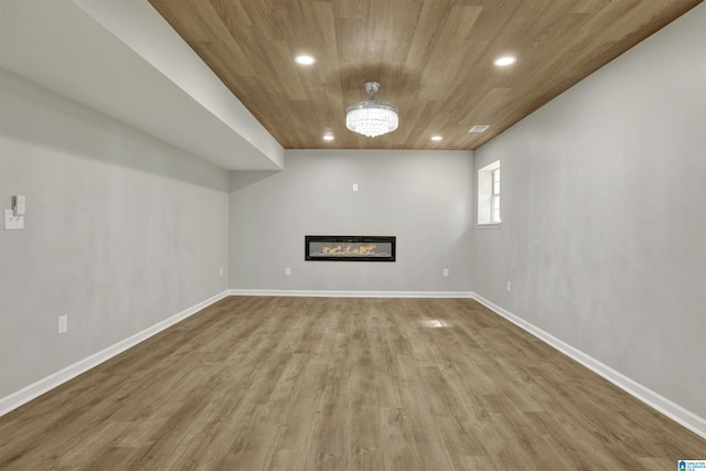 basement featuring an inviting chandelier, wood ceiling, and hardwood / wood-style flooring