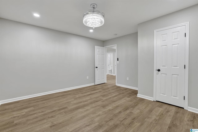 empty room featuring light hardwood / wood-style flooring and a notable chandelier