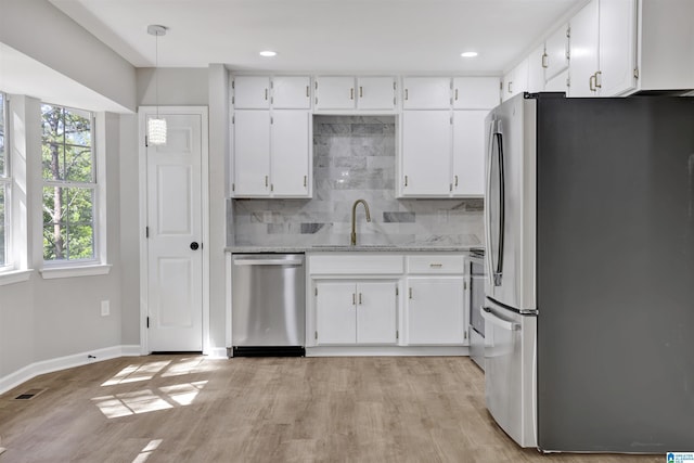 kitchen with white cabinets, sink, appliances with stainless steel finishes, tasteful backsplash, and decorative light fixtures