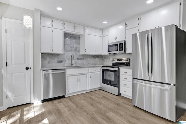 kitchen with decorative backsplash, sink, white cabinetry, and stainless steel appliances