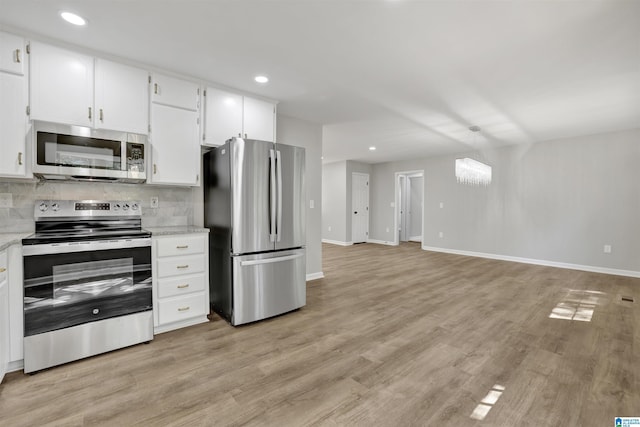 kitchen featuring white cabinetry, stainless steel appliances, an inviting chandelier, backsplash, and light hardwood / wood-style floors