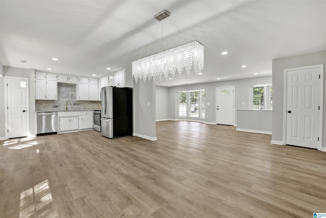 kitchen featuring stainless steel appliances, an inviting chandelier, backsplash, decorative light fixtures, and white cabinets