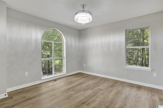 unfurnished room with wood-type flooring and an inviting chandelier