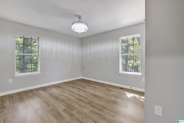 spare room with hardwood / wood-style flooring and a notable chandelier