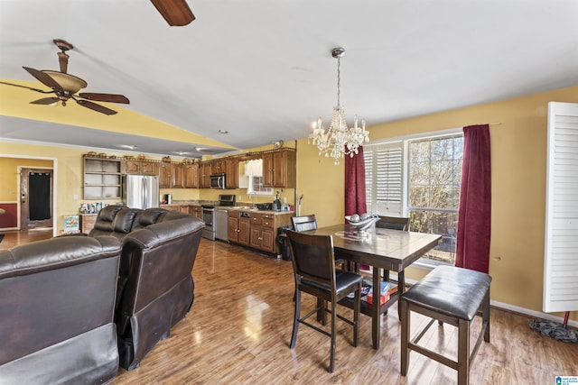 dining area featuring sink, vaulted ceiling, ceiling fan with notable chandelier, and light hardwood / wood-style floors