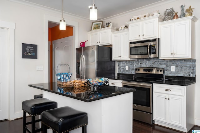 kitchen with white cabinetry, decorative light fixtures, an island with sink, stainless steel appliances, and decorative backsplash