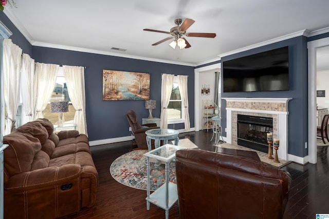 living room with dark wood-type flooring, ceiling fan, ornamental molding, and a fireplace