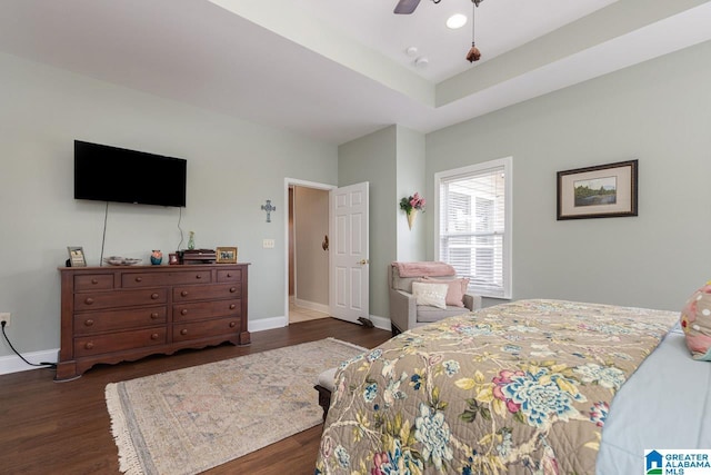 bedroom with ceiling fan, a raised ceiling, and dark hardwood / wood-style floors