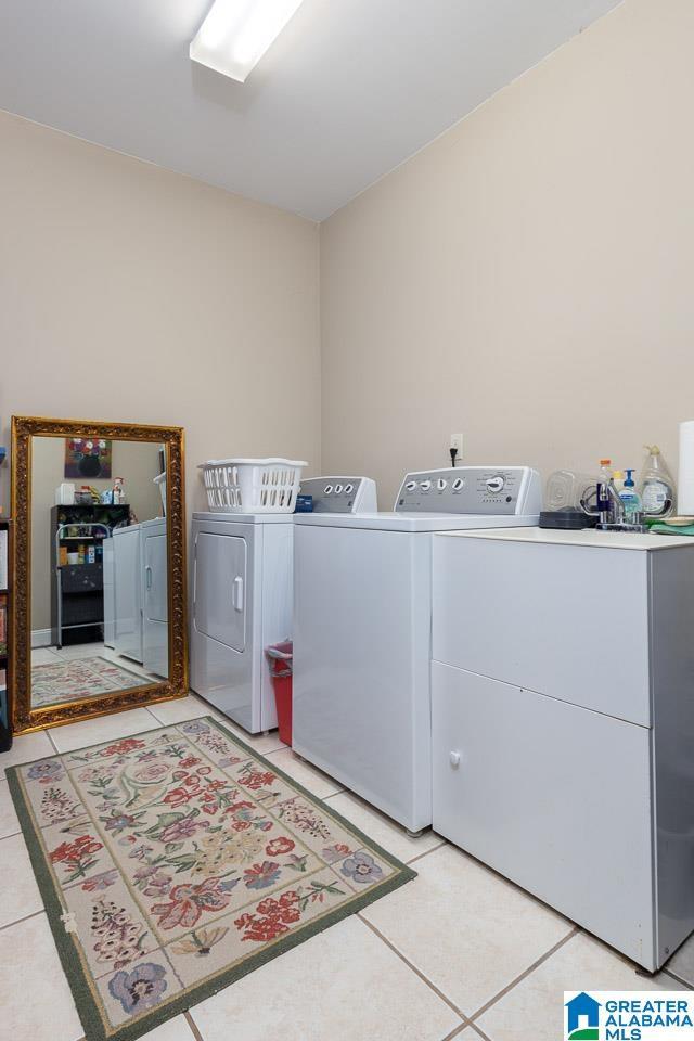 clothes washing area featuring light tile patterned flooring and washing machine and clothes dryer