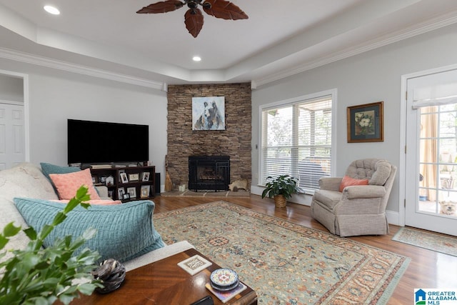 living room featuring ceiling fan, ornamental molding, hardwood / wood-style flooring, and a tray ceiling