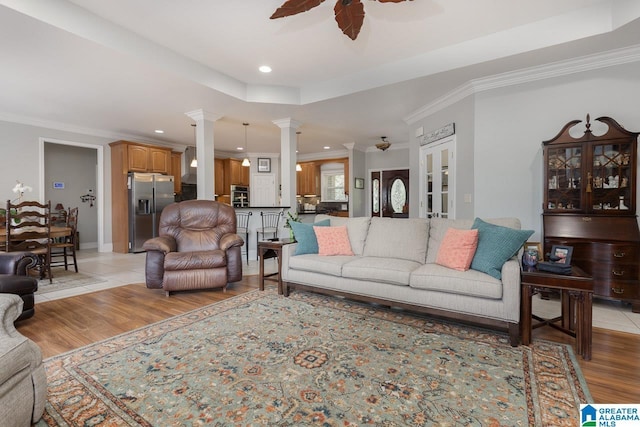 living room with ornate columns, light wood-type flooring, ceiling fan, and crown molding