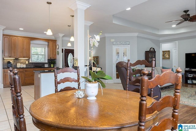 dining space with ceiling fan, a raised ceiling, crown molding, and light tile patterned floors