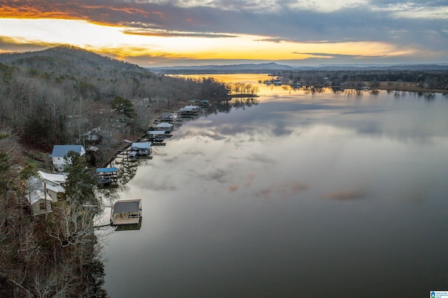 aerial view at dusk featuring a water and mountain view