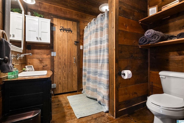 bathroom featuring curtained shower, wooden walls, vanity, and toilet