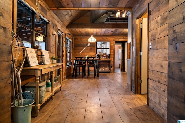 hall featuring vaulted ceiling, a notable chandelier, wooden walls, hardwood / wood-style floors, and wooden ceiling