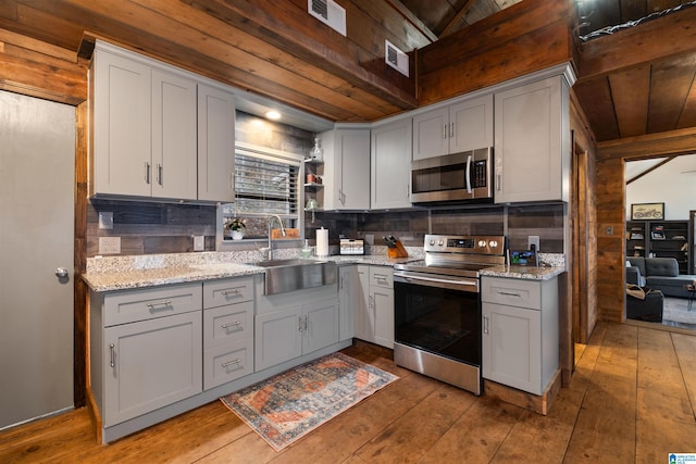 kitchen featuring stainless steel appliances, sink, wooden ceiling, light hardwood / wood-style flooring, and light stone countertops