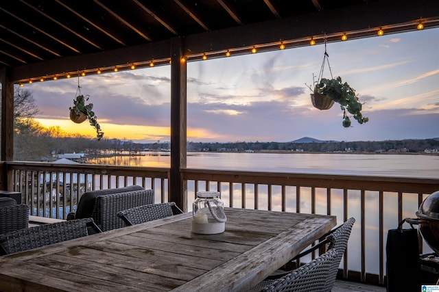 deck at dusk featuring grilling area and a water view