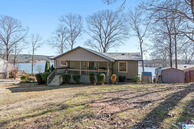 view of front of house with a water view, covered porch, and a shed