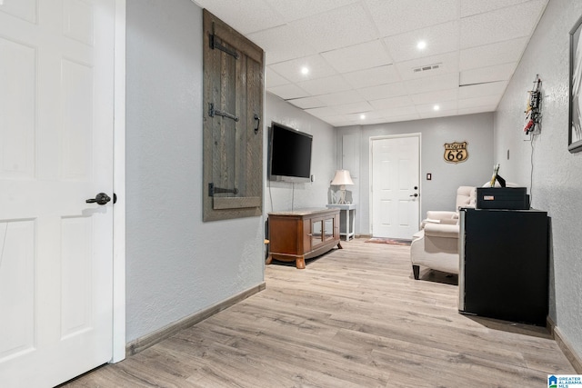 living room featuring a paneled ceiling and light hardwood / wood-style flooring