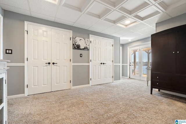 unfurnished bedroom with coffered ceiling and light colored carpet